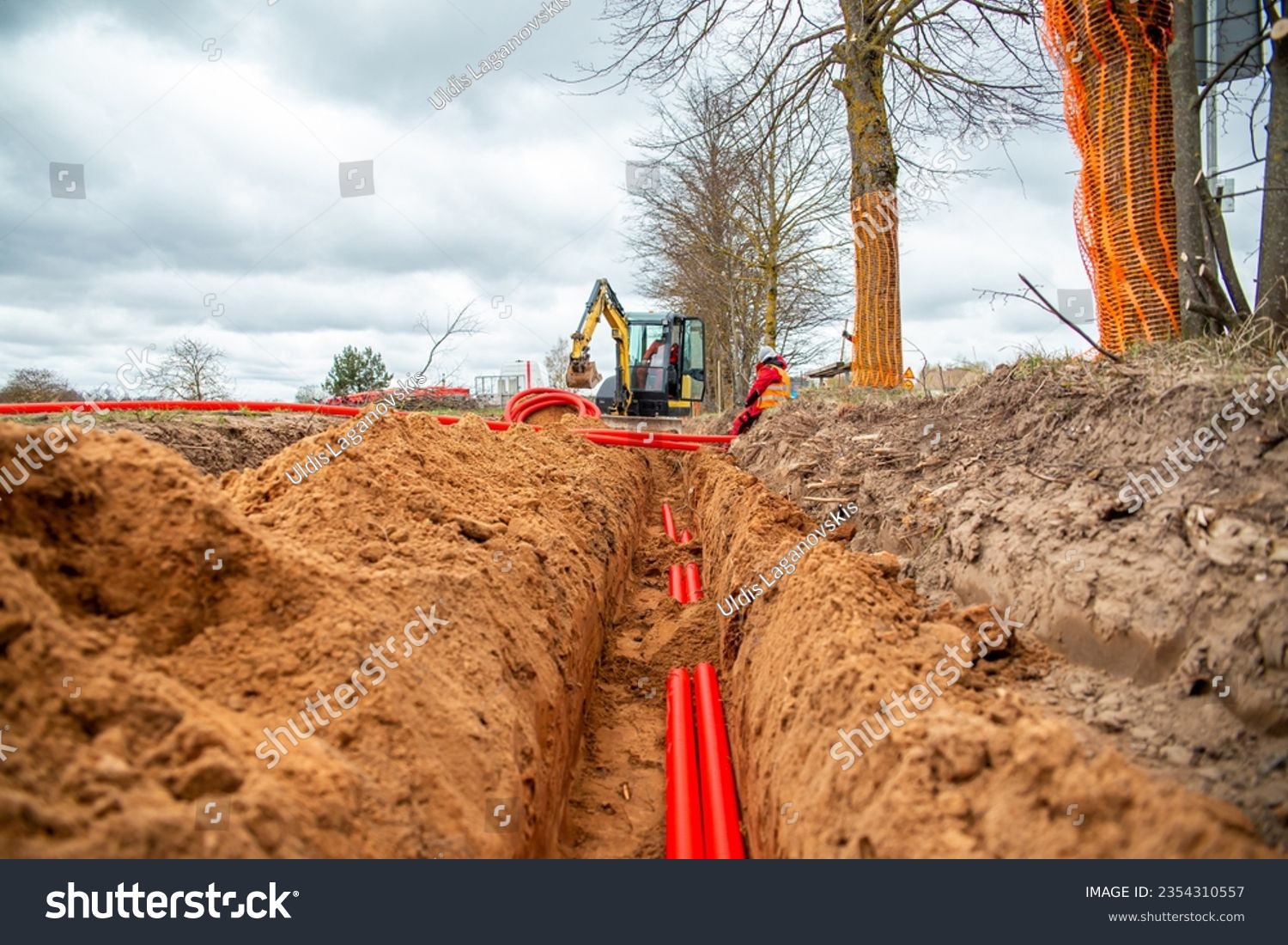 Network cables in red corrugated pipe are buried underground on the street. underground electric cable infrastructure installation.  #2354310557