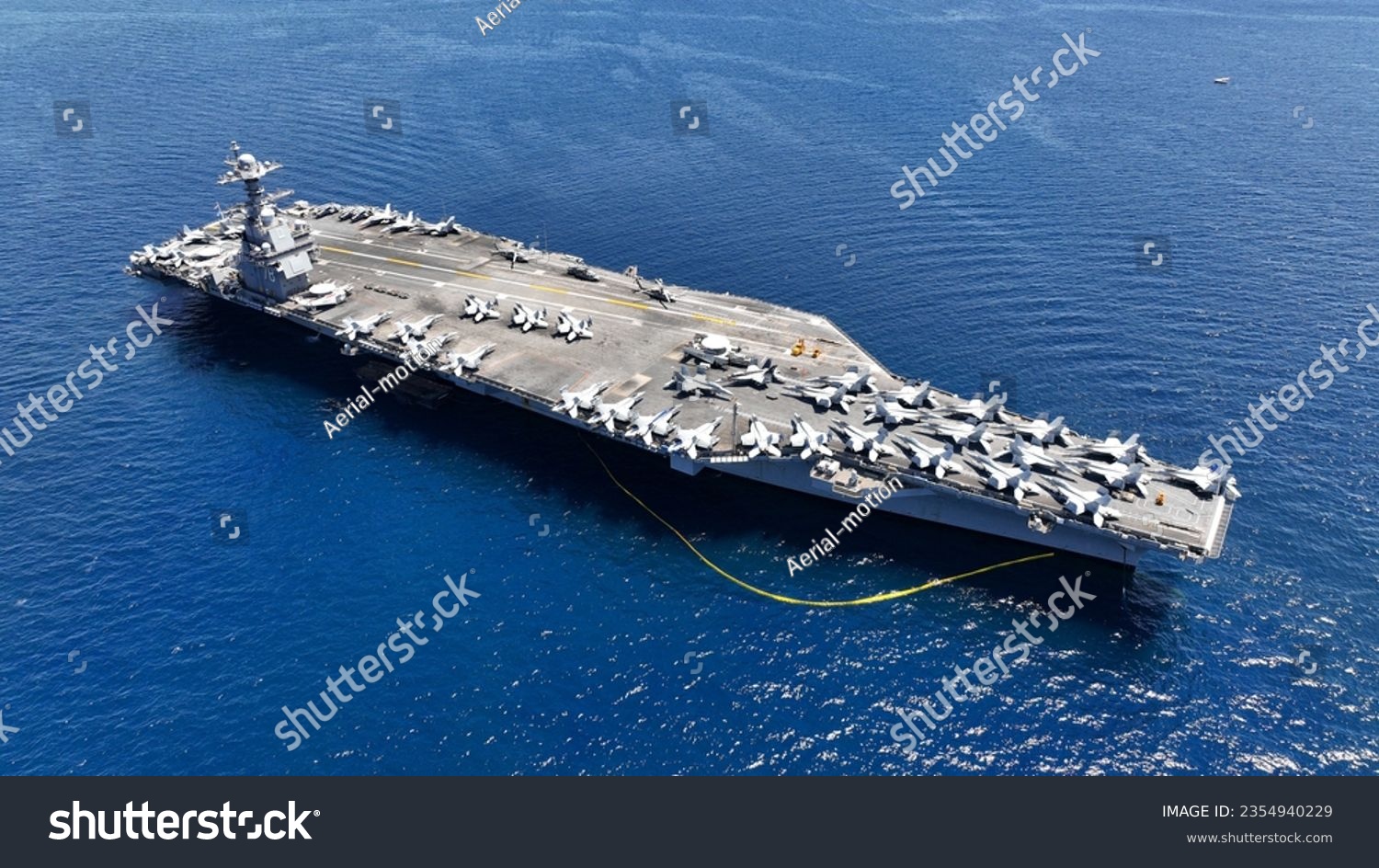 Aerial drone photo of USS Gerald R. Ford latest technology nuclear powered aircraft carrier anchored in deep blue open ocean sea #2354940229