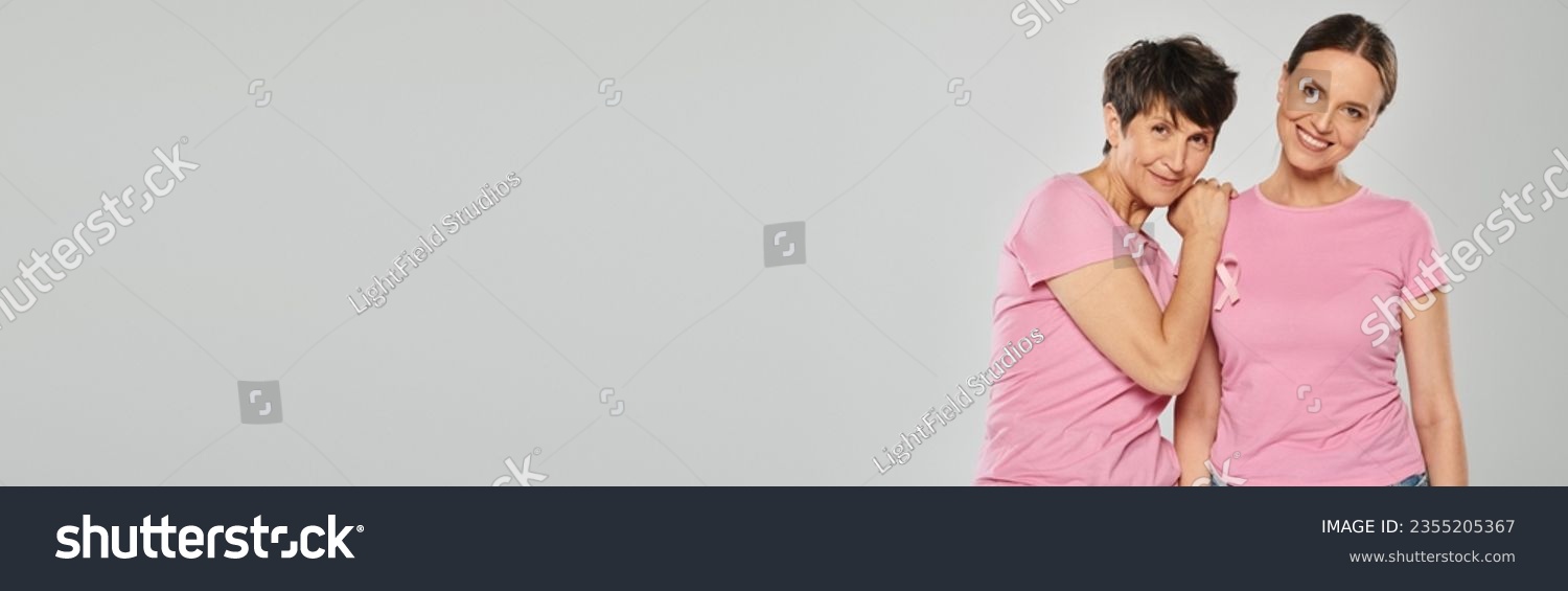 breast cancer awareness concept, two women with pink ribbons on grey backdrop, cancer free, banner #2355205367