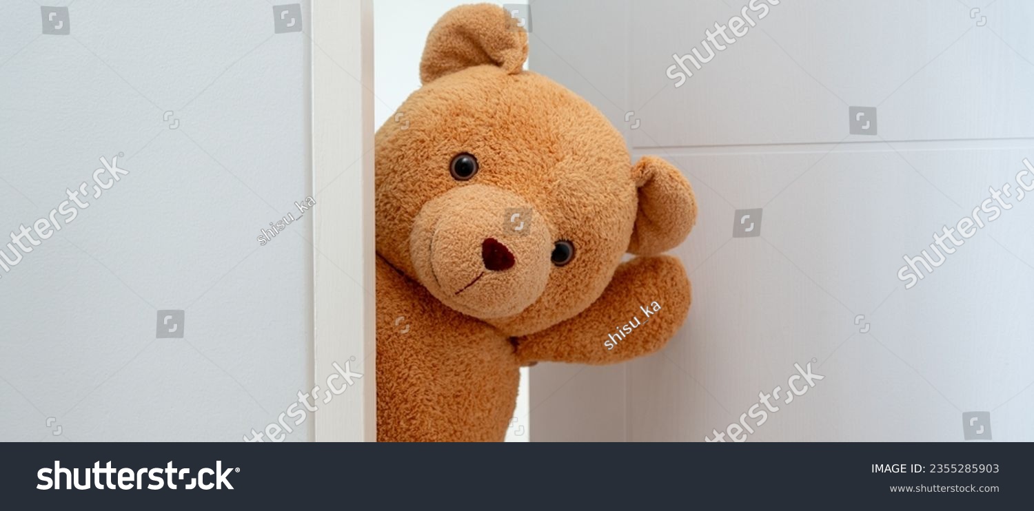 Cute brown Teddy bear toy sneak behind the door and surprise to congratulate the special day holiday festivals. game child, day care, welcome, kid day, shy childhood, party funny, stuffed doll #2355285903