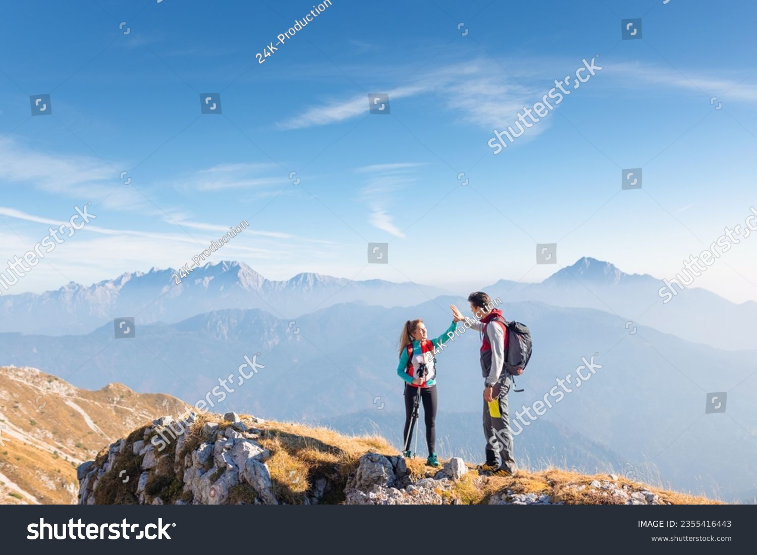 Epic view of mountain ridge and range in the haze under the sun and victory gesture high five hands of hiker couple. Motivation, support, love, and success concepts. #2355416443