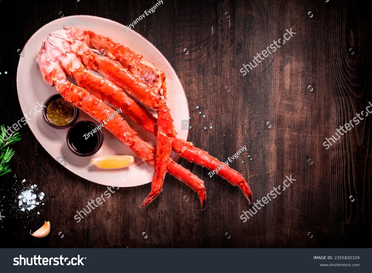 White plate with boiled claws of kamchatka crab, lemon and butter over light-blue stone background, studio shot #2355820329