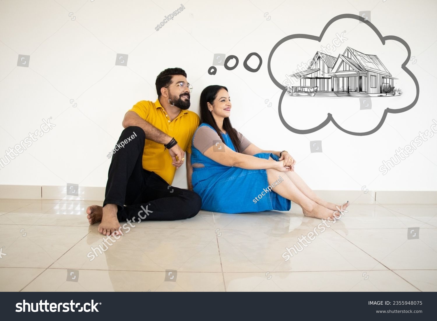 Young Indian Couple Sitting On Floor Thinking Of Getting Their Own House. Real Estate Concept. #2355948075