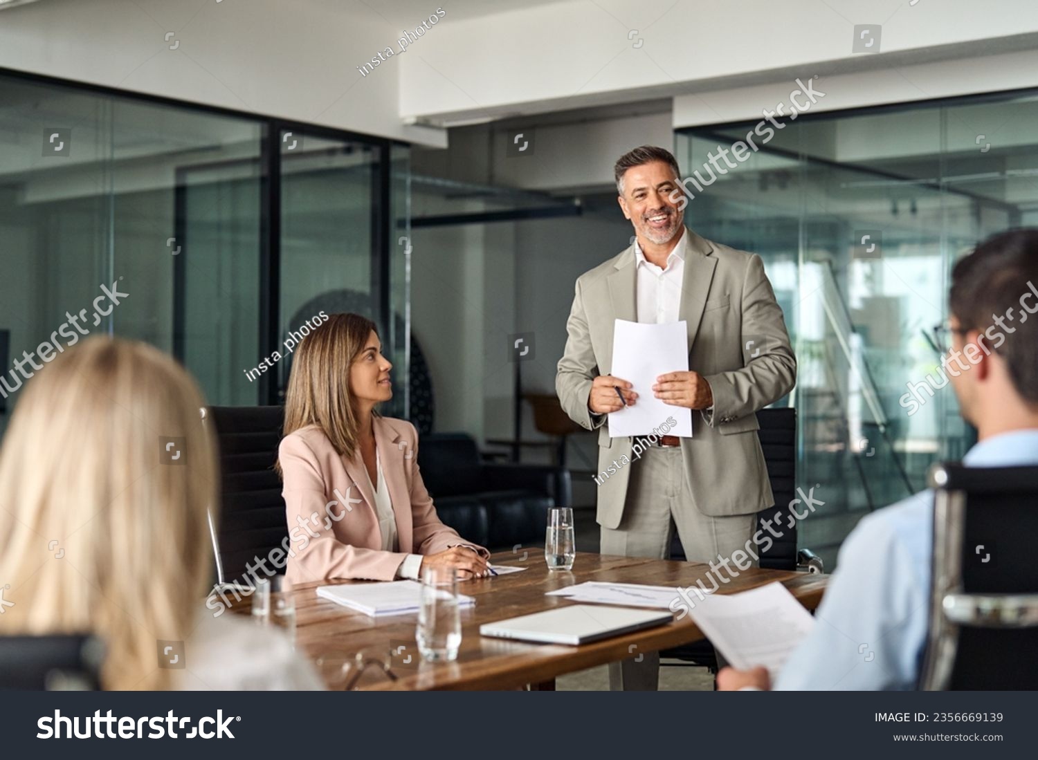 Happy mature older Latin business man team manager CEO executive leading group corporate meeting in board room. Diverse business team people company staff working together at office table. #2356669139