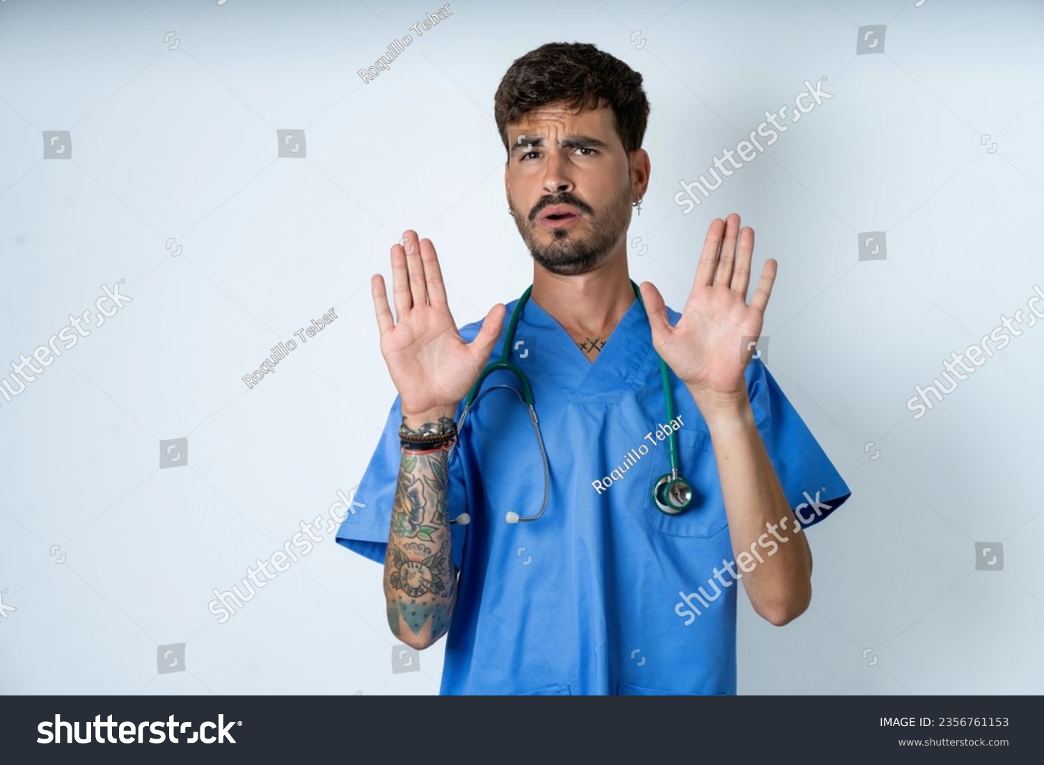 young caucasian doctor man wearing blue medical uniform Moving away hands palms showing refusal and denial with afraid and disgusting expression. Stop and forbidden. #2356761153