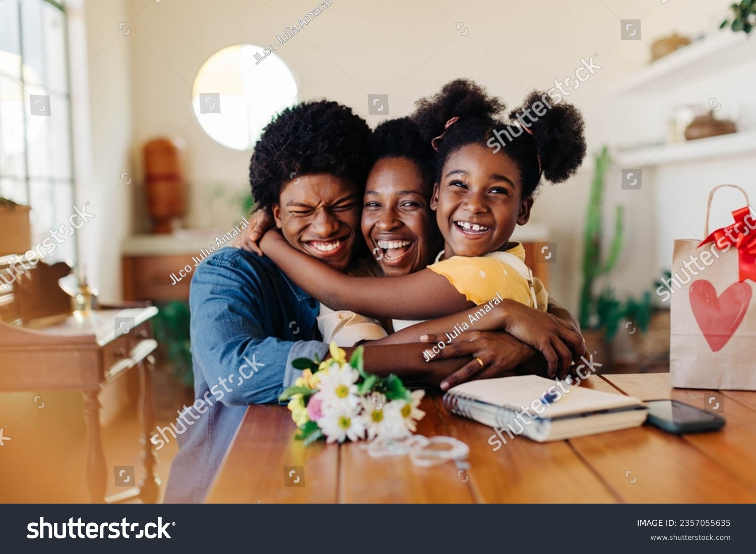 Happy family celebrating together at home. Kids give their mom a bouquet of flowers, bringing joy and love. Special moment showing the beauty of motherhood and the happiness found in simple gestures. #2357055635