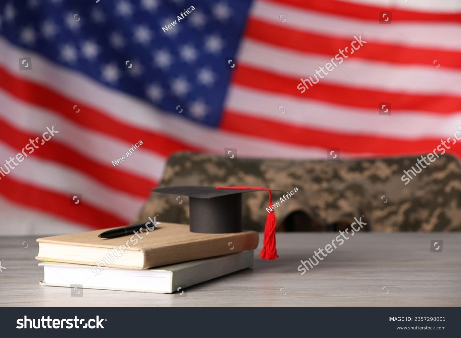 Notebooks, mortarboard and pen on wooden table against flag of USA, space for text. Military education #2357298001