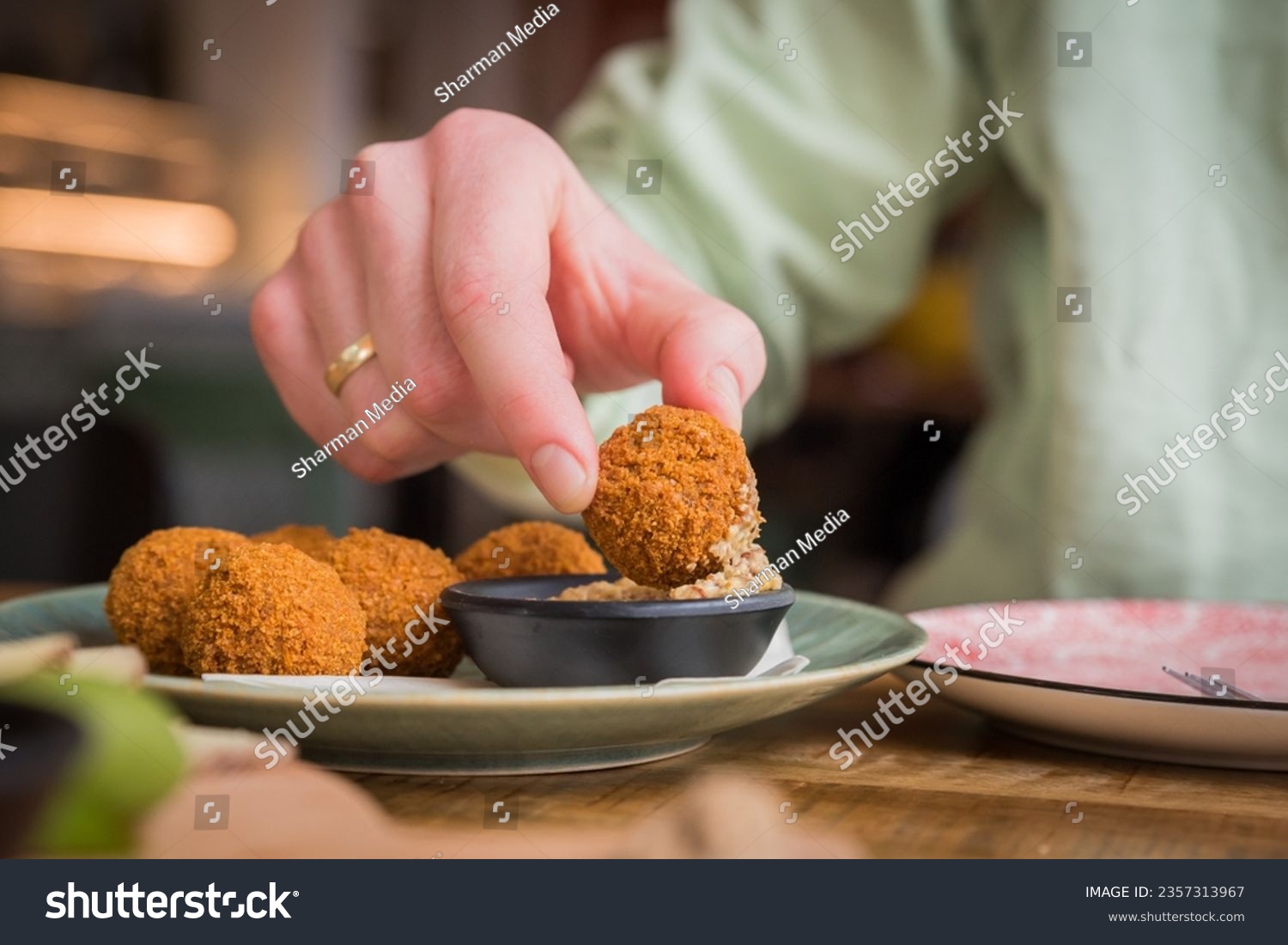Close up of traditional Dutch bitterballen being dipped in mustard in a café restaurant #2357313967