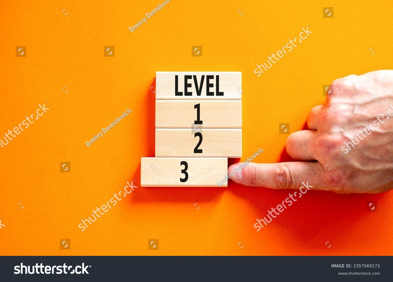 Time to level 3 symbol. Concept word Level 1 2 3 on wooden block. Businessman hand. Beautiful orange table orange background. Business planning and time to level 3 concept. Copy space. #2357569173
