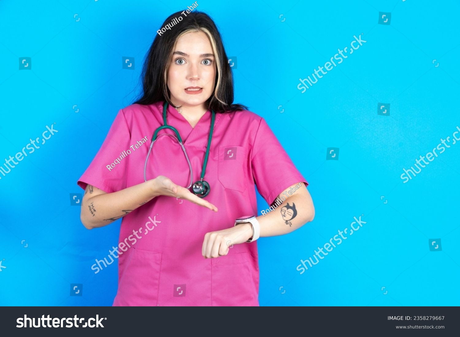 Young caucasian doctor woman wearing pink uniform In hurry pointing to watch time, impatience, upset and angry for deadline delay. #2358279667