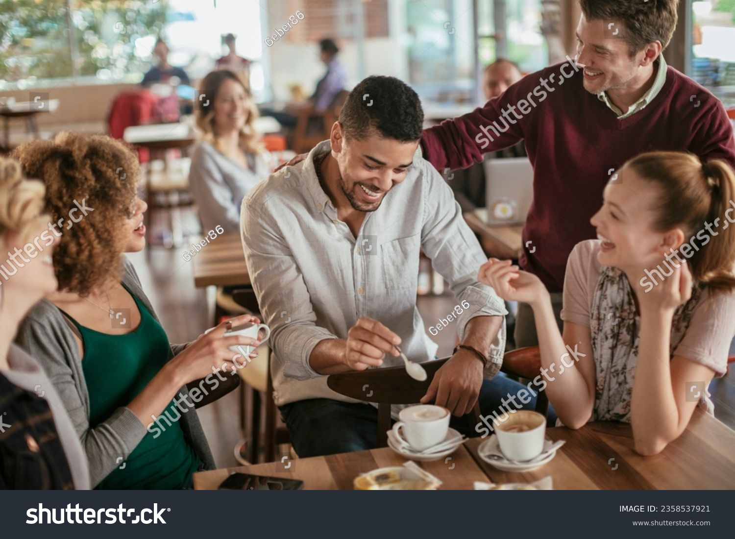 Young and diverse group of people talking while having coffee together in a cafe #2358537921