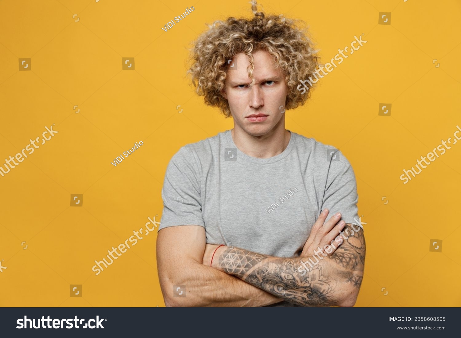 Young sad displeased dissatisfied depressed caucasian man 20s he wear grey t-shirt hold hands crossed folded look camera isolated on plain yellow background studio portrait. People lifestyle concept #2358608505