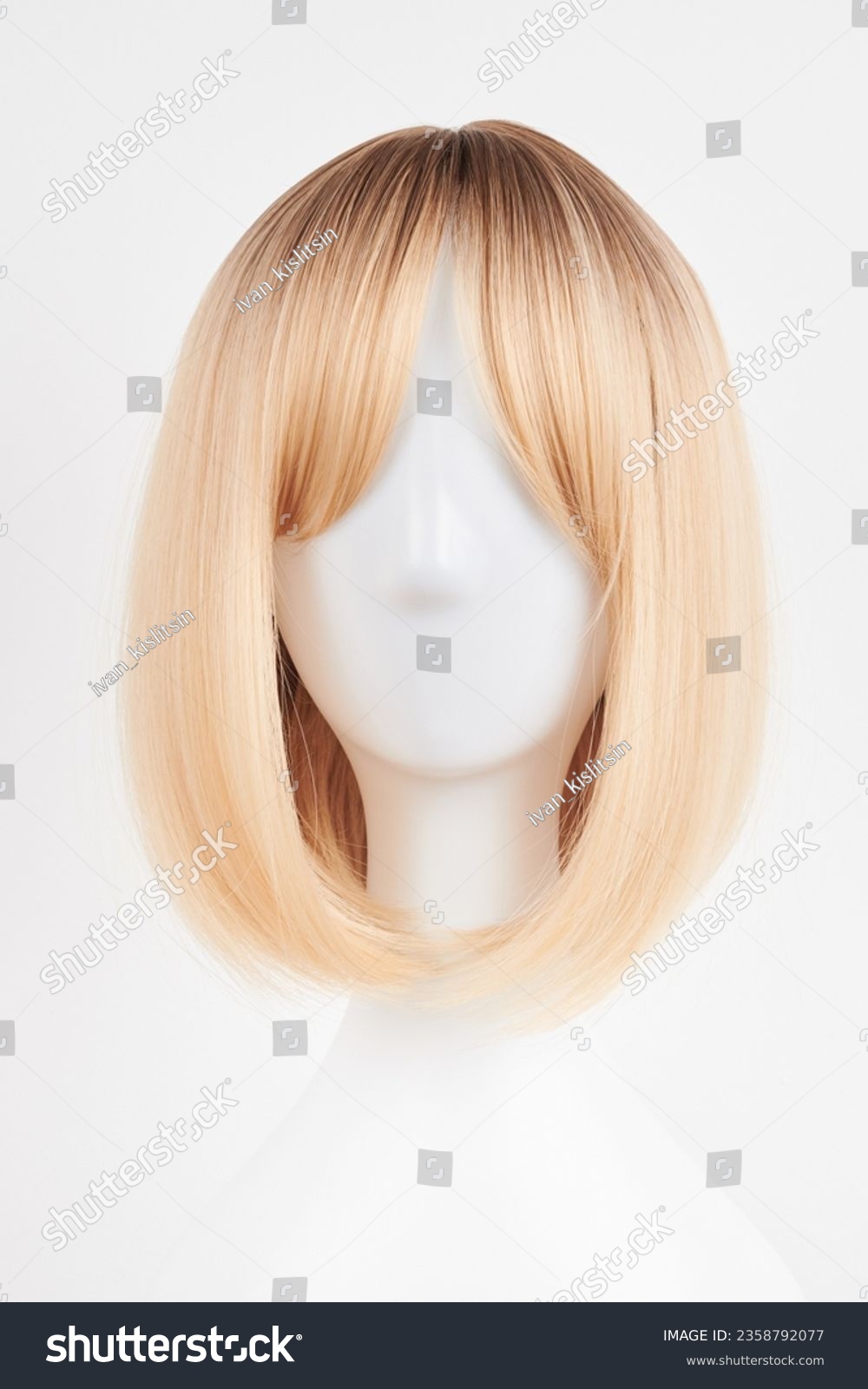 Natural looking blonde fair wig on white mannequin head. Short hair cut on the plastic wig holder isolated on white background, front view
 #2358792077