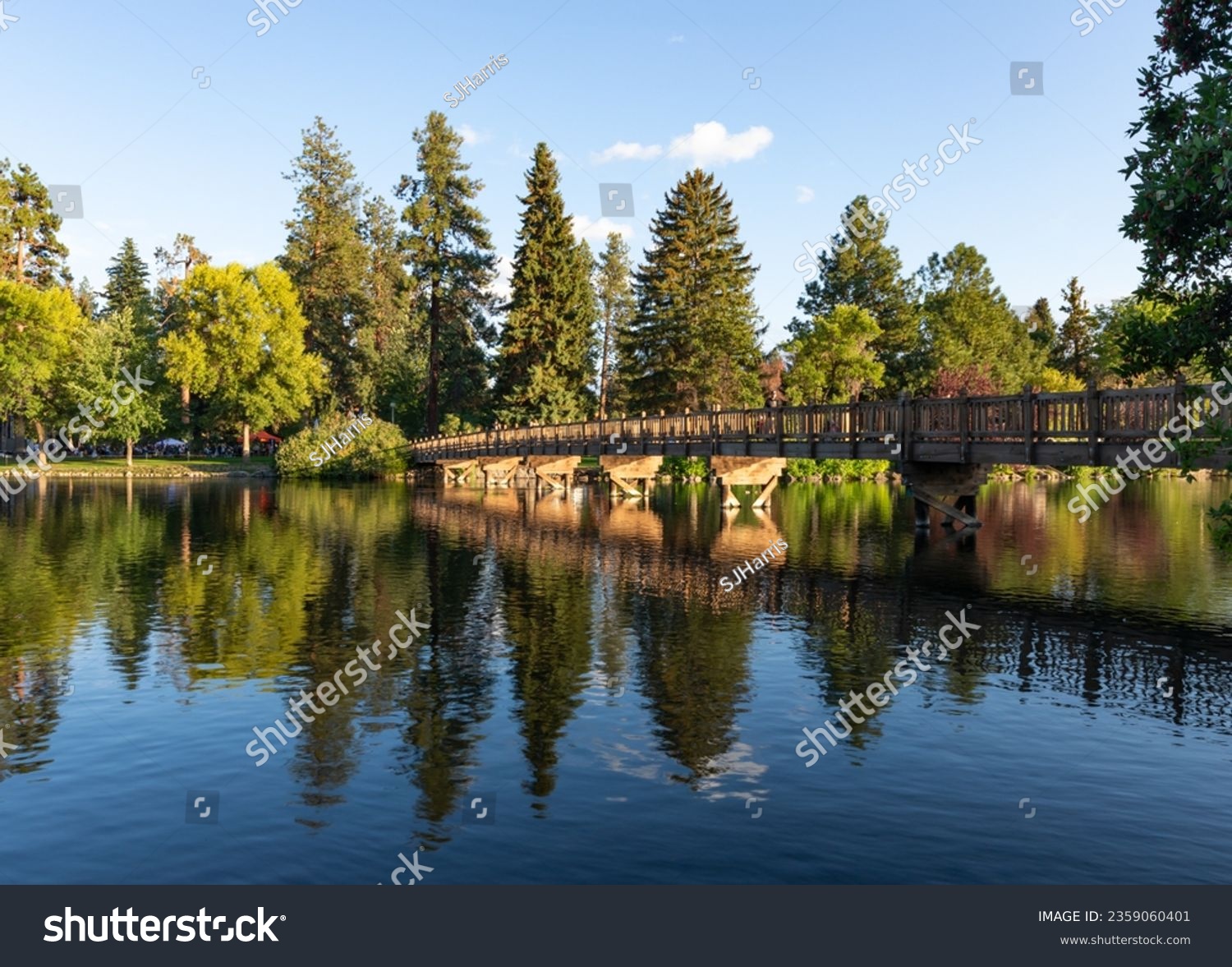 Beautiful and tranquil lush wide angle view of bridge over Mirror Pond in Drake Park, Bend, Oregon, on a blue sky sunny summer afternoon. #2359060401