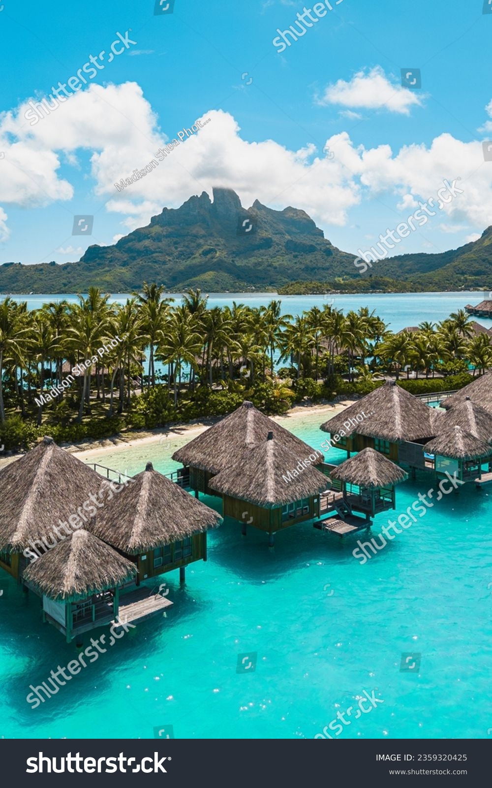 Aerial drone shot of the tropical island Bora Bora in French Polynesia with a resort, hut, beaches and palm trees  #2359320425