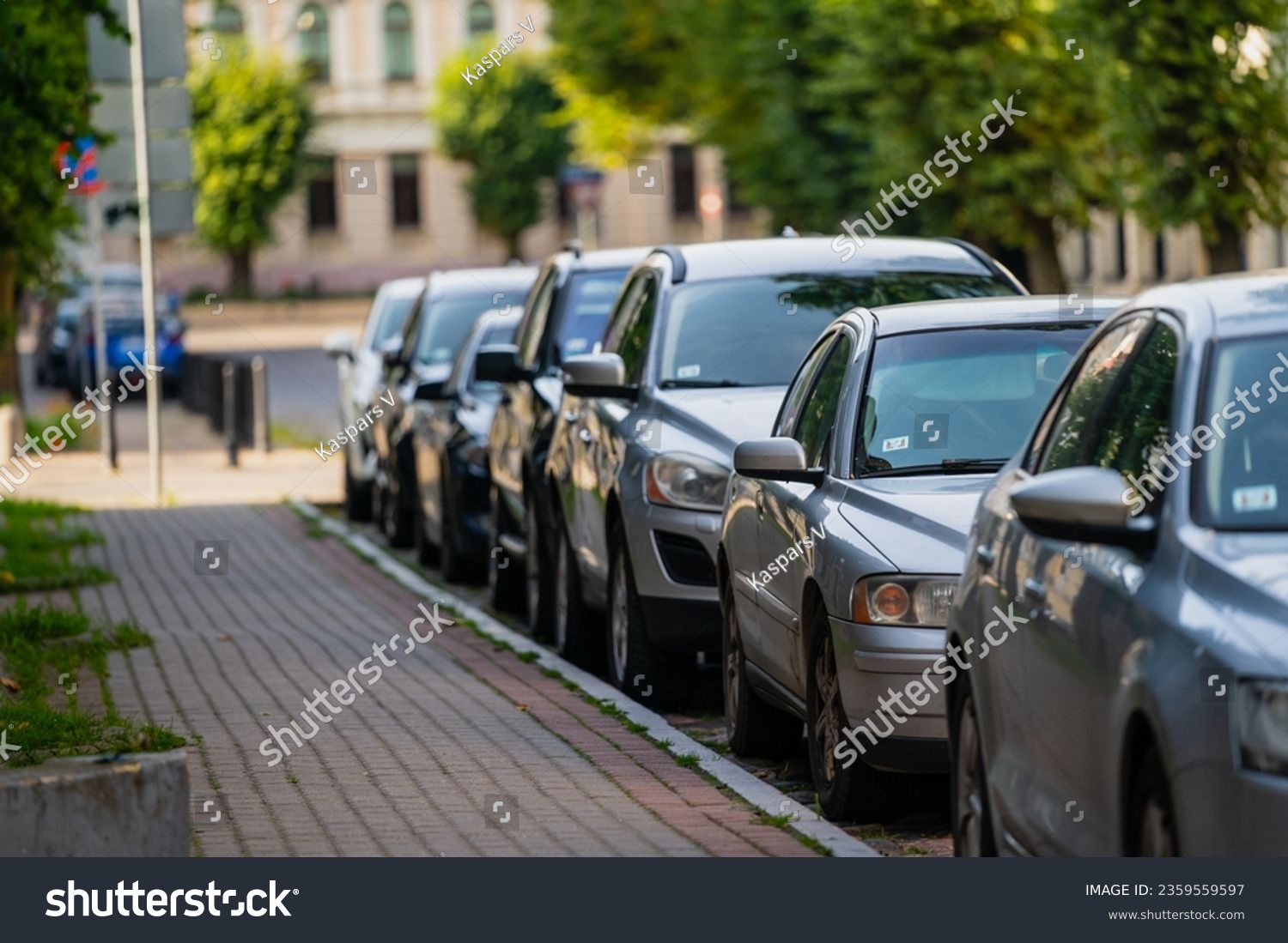 Cars parked next to a paved side walk in afternoon #2359559597