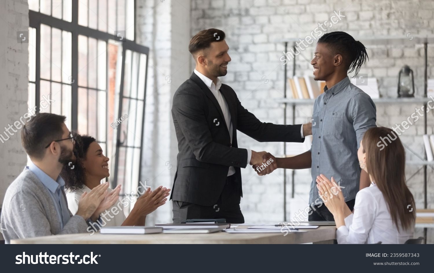 Smiling Caucasian businessman shake hand congratulate with good work achievement result african American male employee, boss handshake greeting with promotion excited biracial worker at meeting #2359587343
