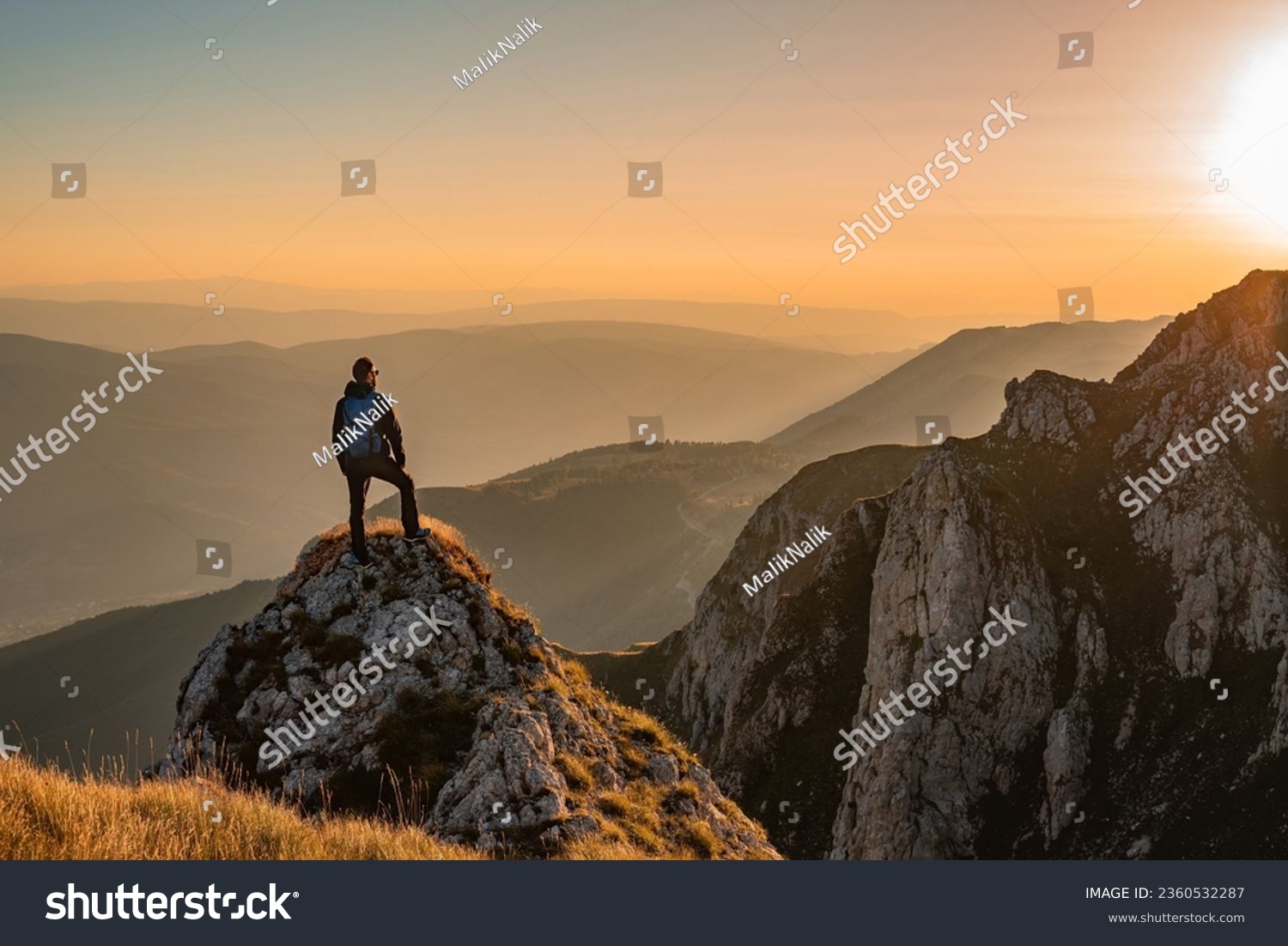 A man who hikers enjoys a break look at the top of the mountain at sunset adventure travel. #2360532287