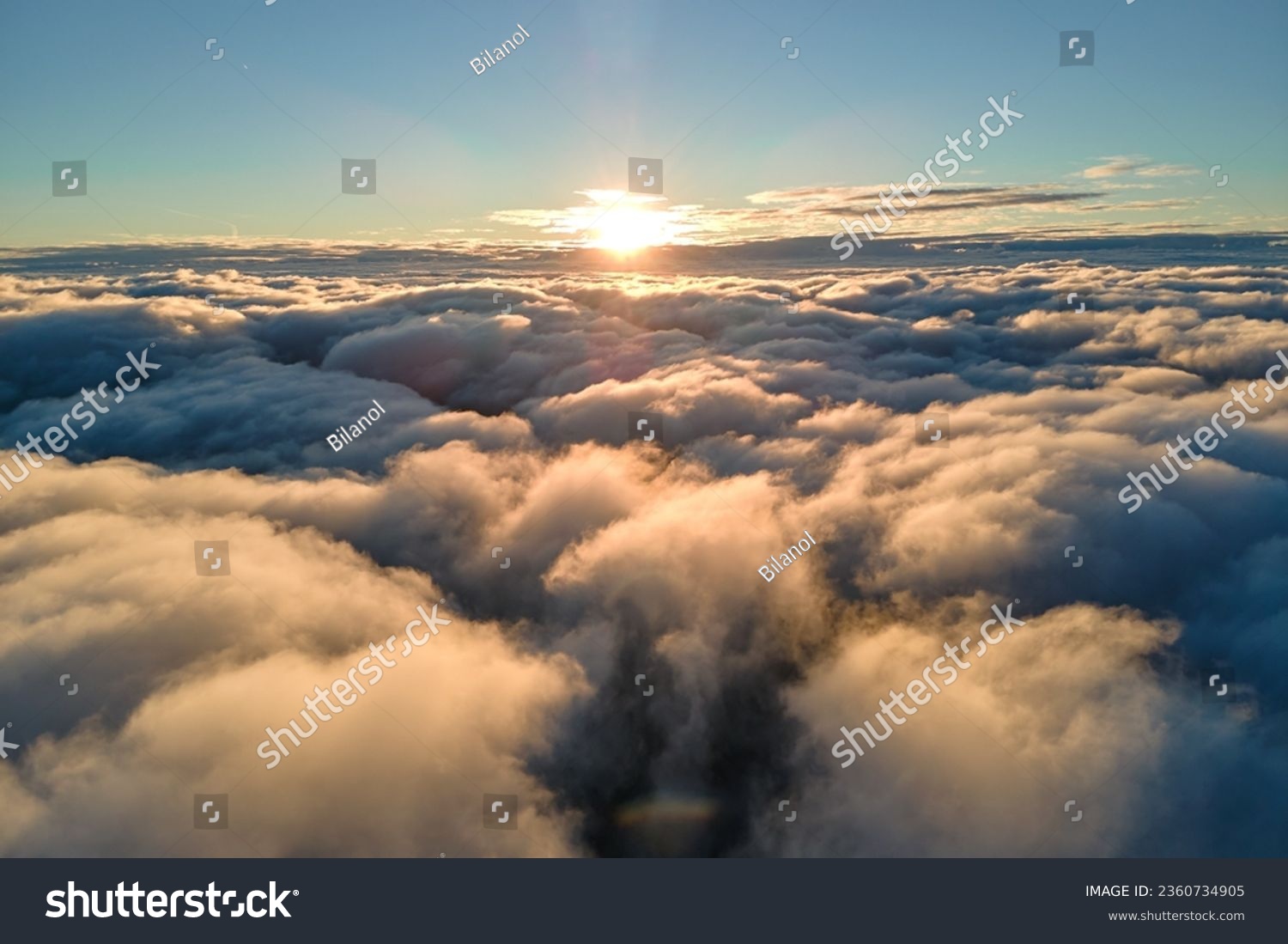 Aerial view from airplane window at high altitude of dense puffy cumulus clouds flying in evening #2360734905
