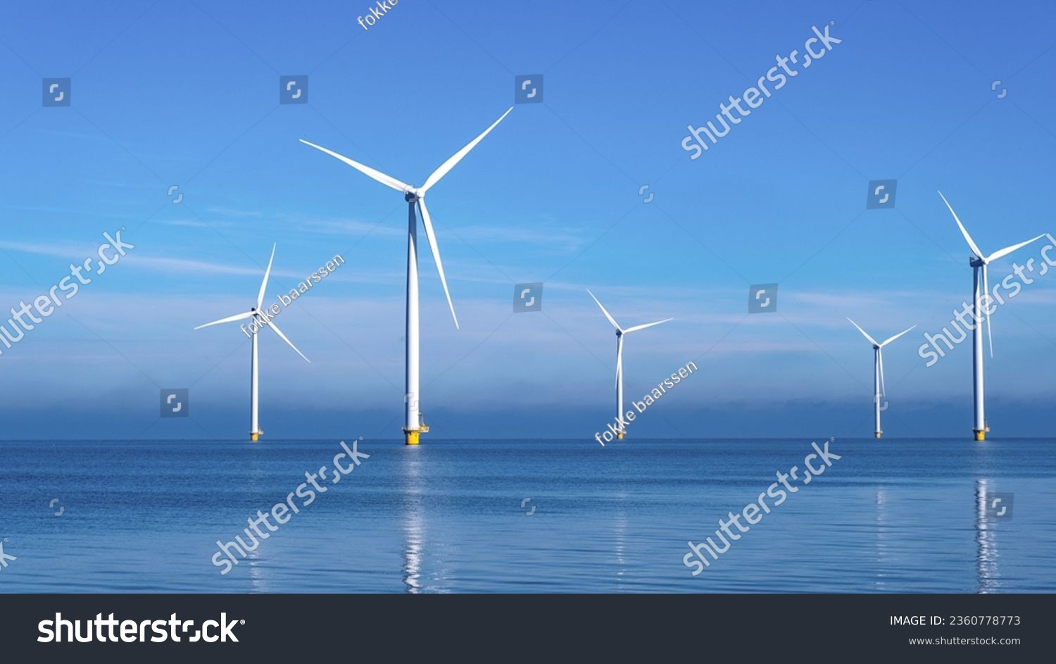 Windmill park with clouds and a blue sky, wind mill turbines in the ocean aerial view of a wind farm in the Nehterlands production clean energy #2360778773