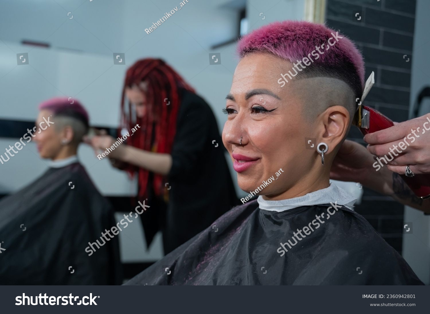 Asian woman with pink hair getting a haircut in a barbershop.  #2360942801