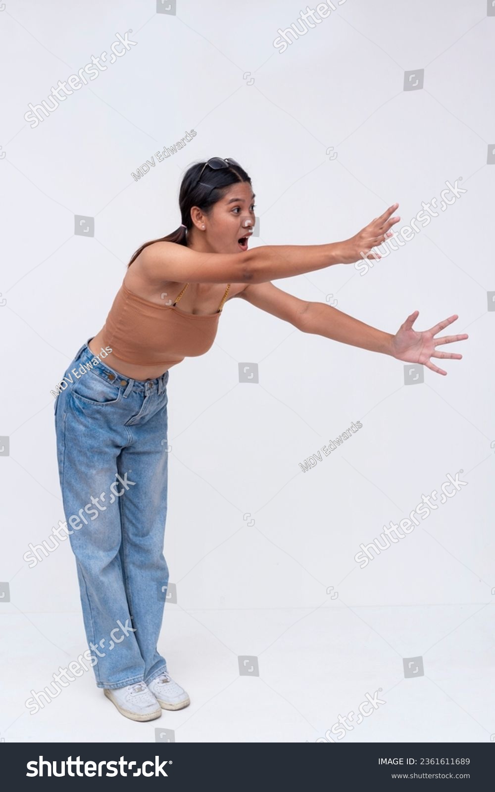 A young asian woman reaching out with her hands, with an excited or desperate look on her face. Isolated on a white background. #2361611689