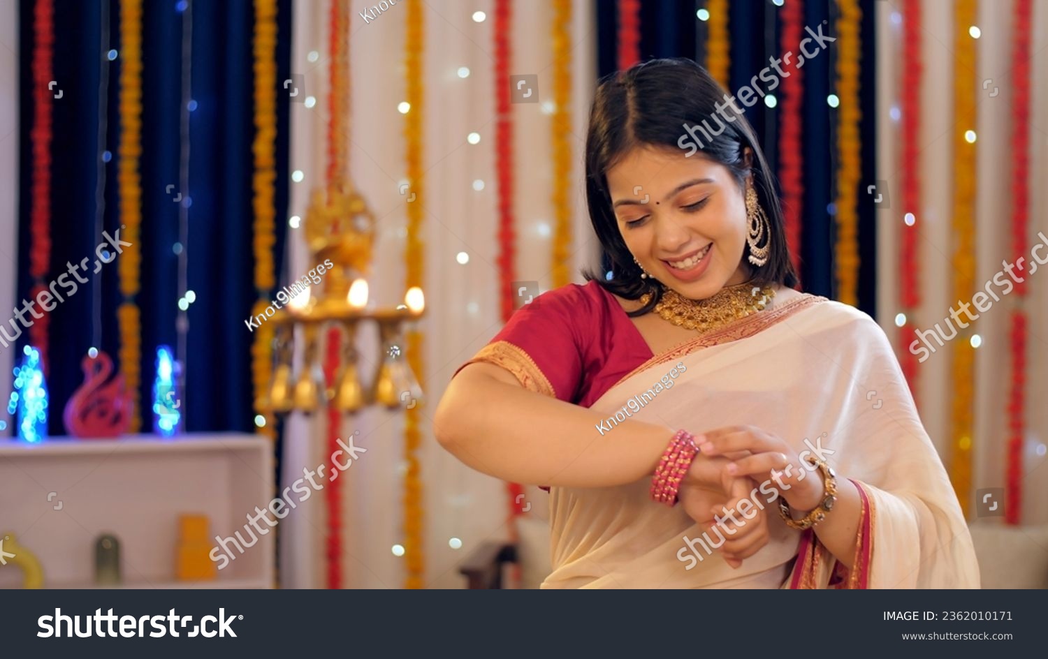 A beautiful Indian woman in an ethnic dress checking her new bangles - woman's accessories, festival celebration. A young woman wearing jewellery and a saree for Diwali festival - traditional dress... #2362010171