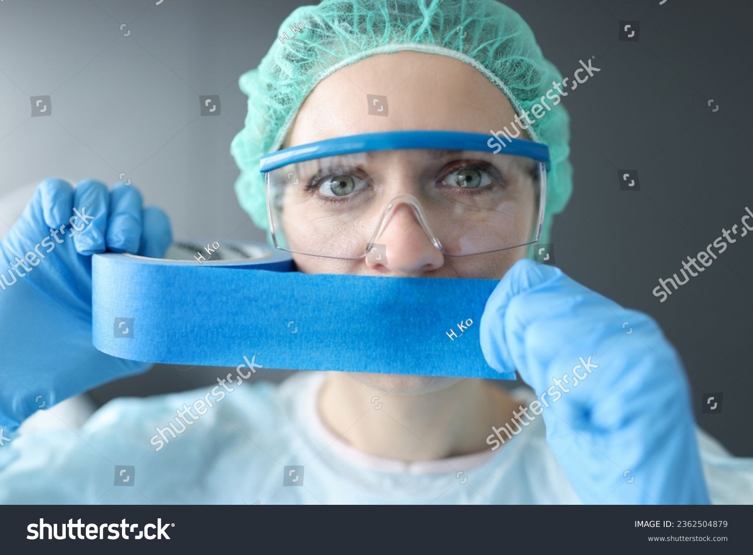 Woman doctor sealing her mouth with blue tape. Medical secrecy concept #2362504879