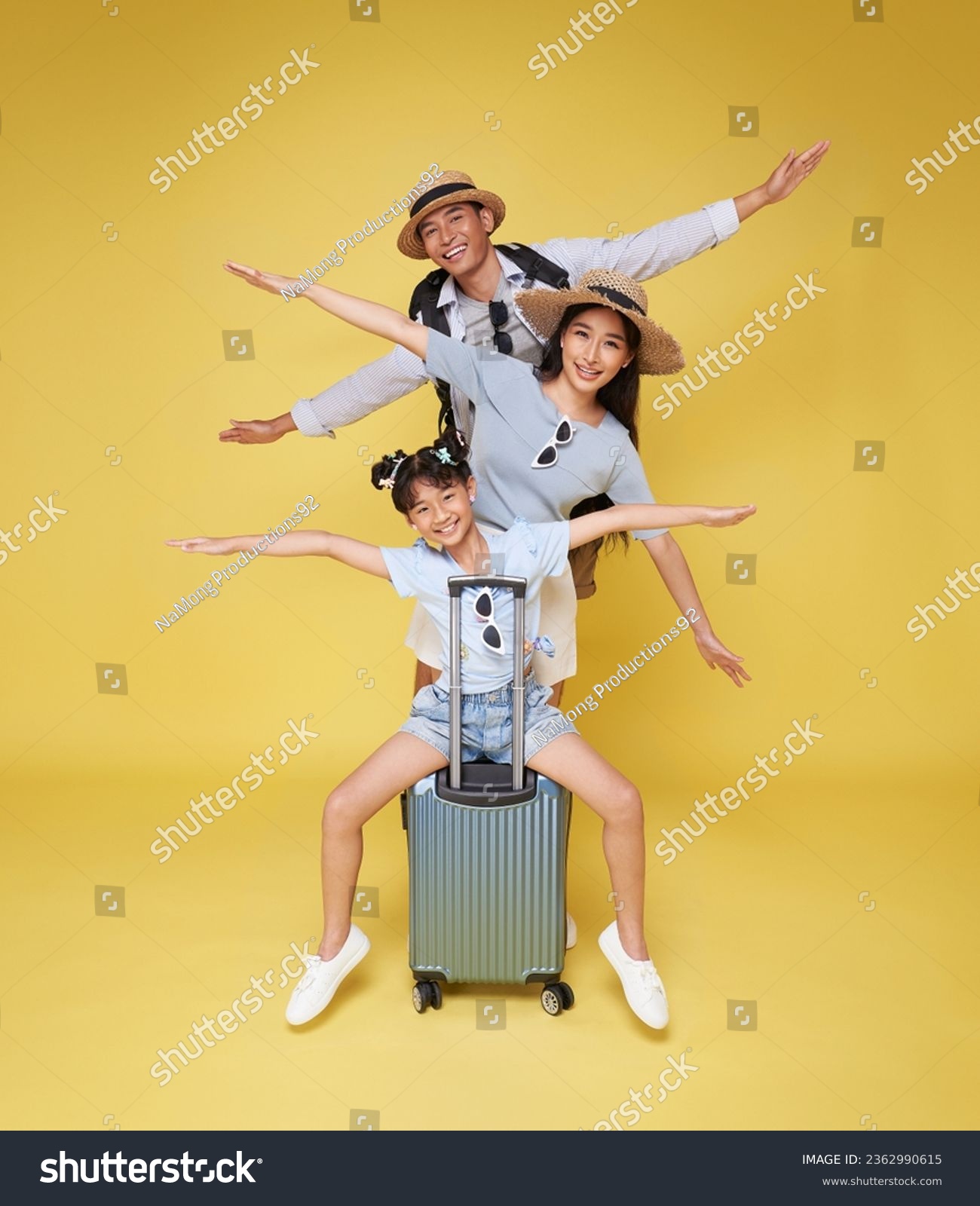 Happy fun asian family vacation portrait. Father, mother and two daughters ready for travel flight with suitcase isolated on yellow studio background. #2362990615