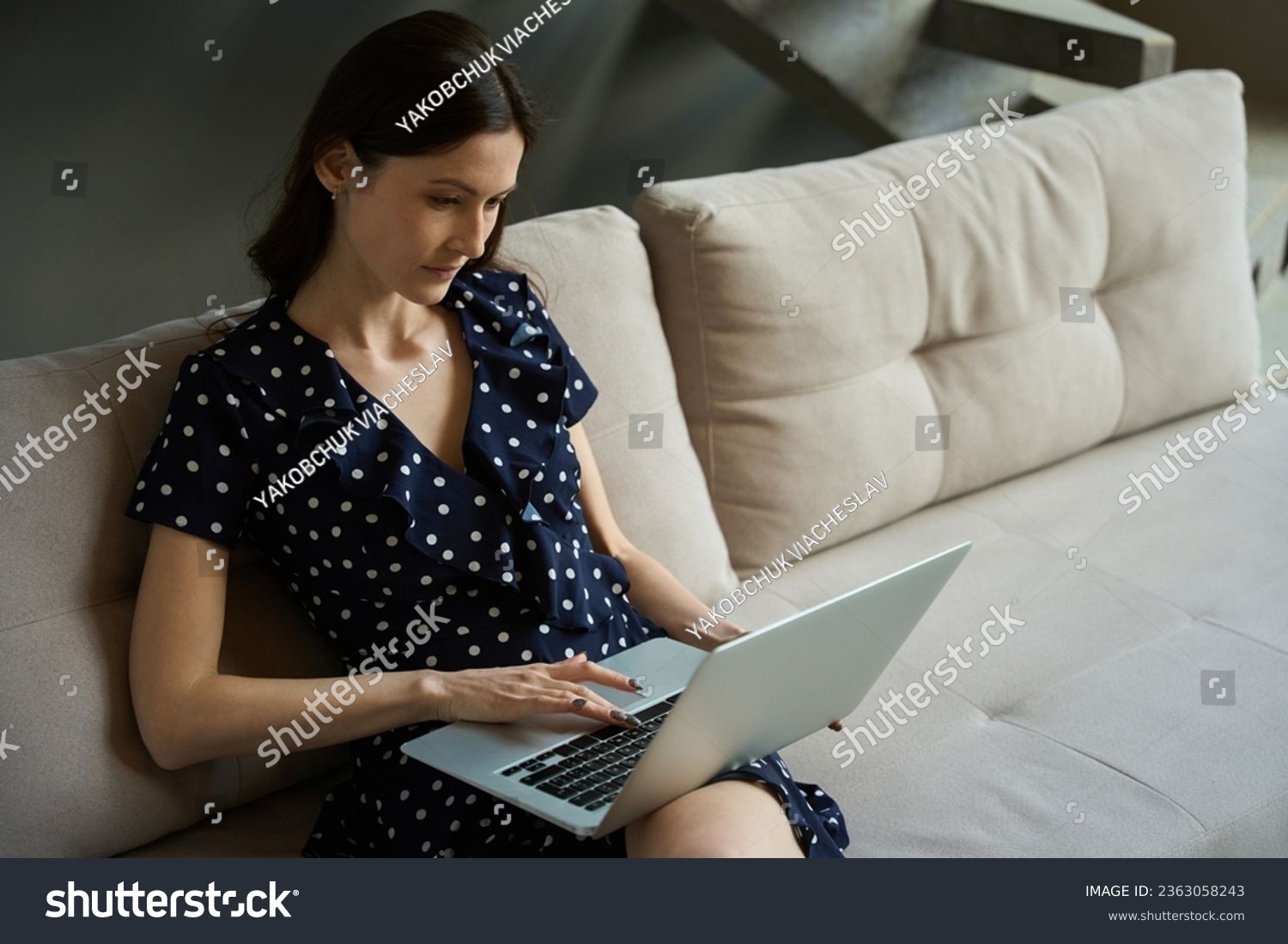 Female sits at home on couch and works on laptop #2363058243
