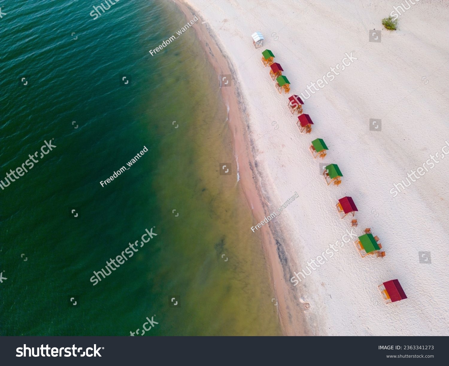 Drone shot of the beach stones tip, a sandy beach with colorful sun shades at the shore of a river with turquoise and clear water: Praia da Ponta de Pedras between Alter do Chão and Santarém in Brasil #2363341273