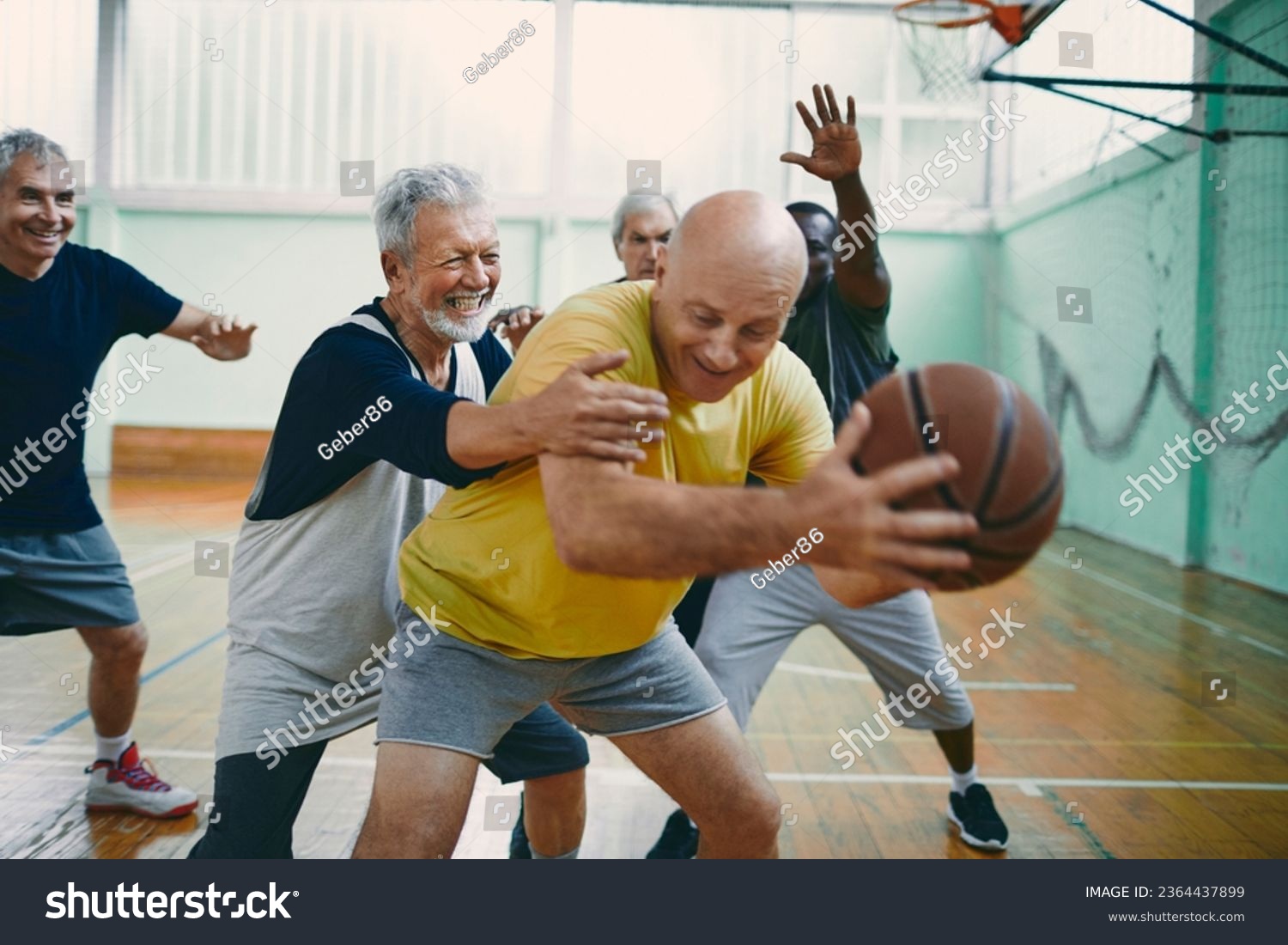Diverse group of male seniors playing basketball in an indoor basketball gym #2364437899