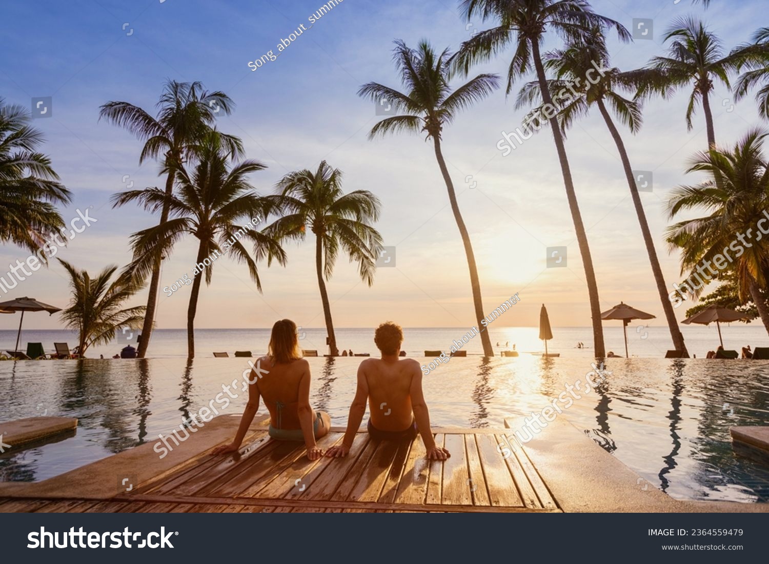 couple on the beach at sunset, honeymoon travel, man and woman sitting near swimming pool in hotel resort #2364559479