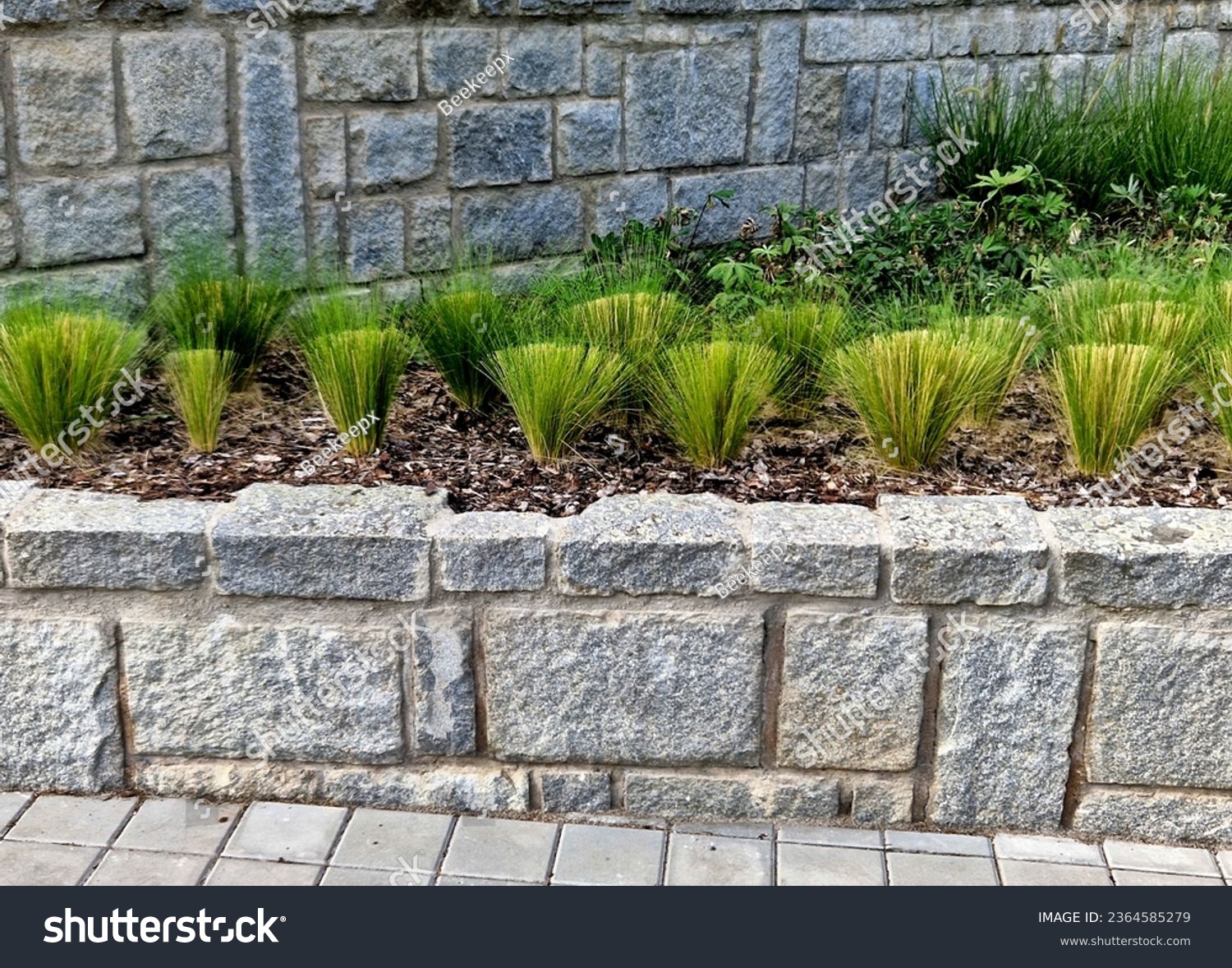 Granite walls made of stone blocks serve as design elements, retaining walls, or seating areas, seats for park visitors. parking for bicycles with metal frames and benches made of horizontal wires #2364585279