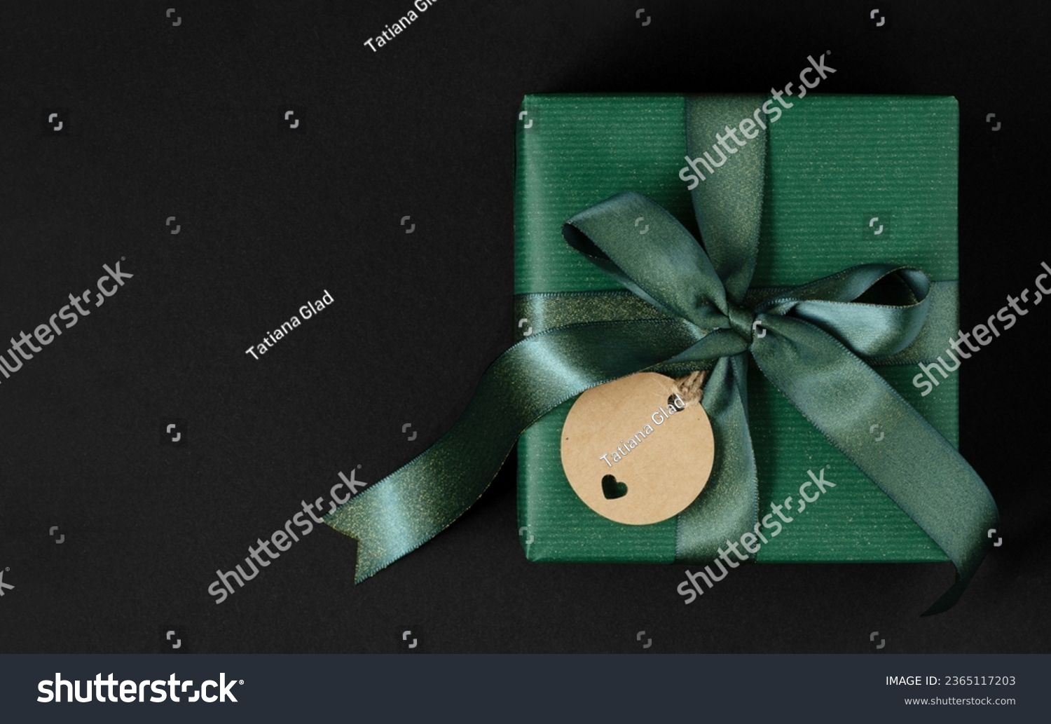 Green gift box with green ribbon and craft brown gift tag. Green background, place for your text #2365117203
