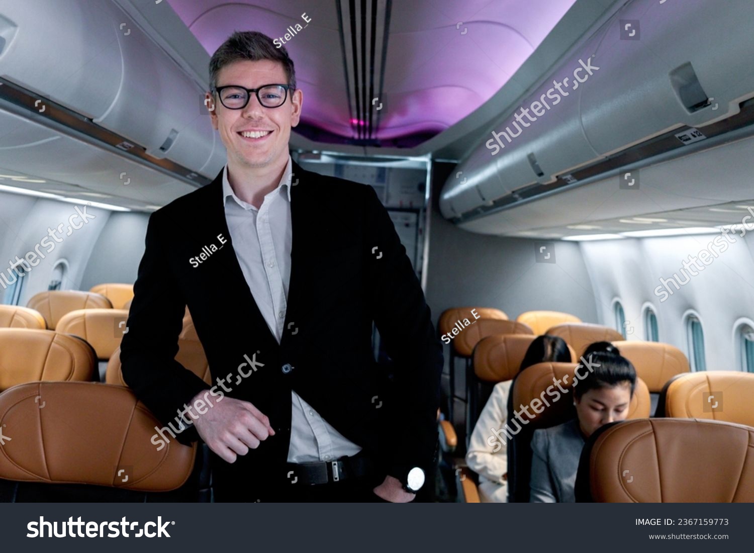 Portrait of happy smiling businessman in black suit, standing on aisle inside airplane, male passenger traveling on business trip by aircraft, businesspeople traveling with airline transportation. #2367159773