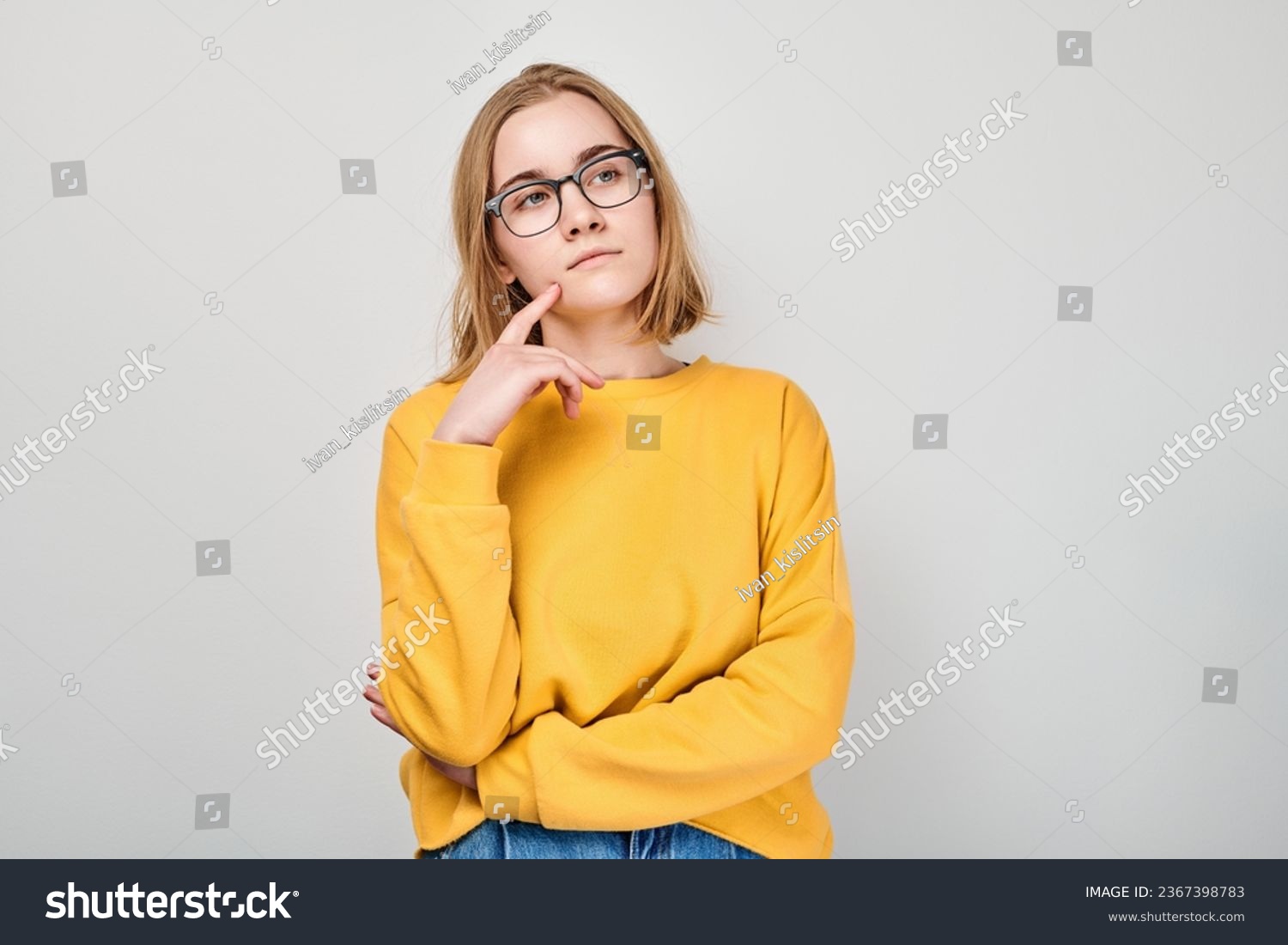 Clever blond student girl with glasses touch chin thinks, chooses isolated on white studio background with copy space. Confidence smart genius #2367398783