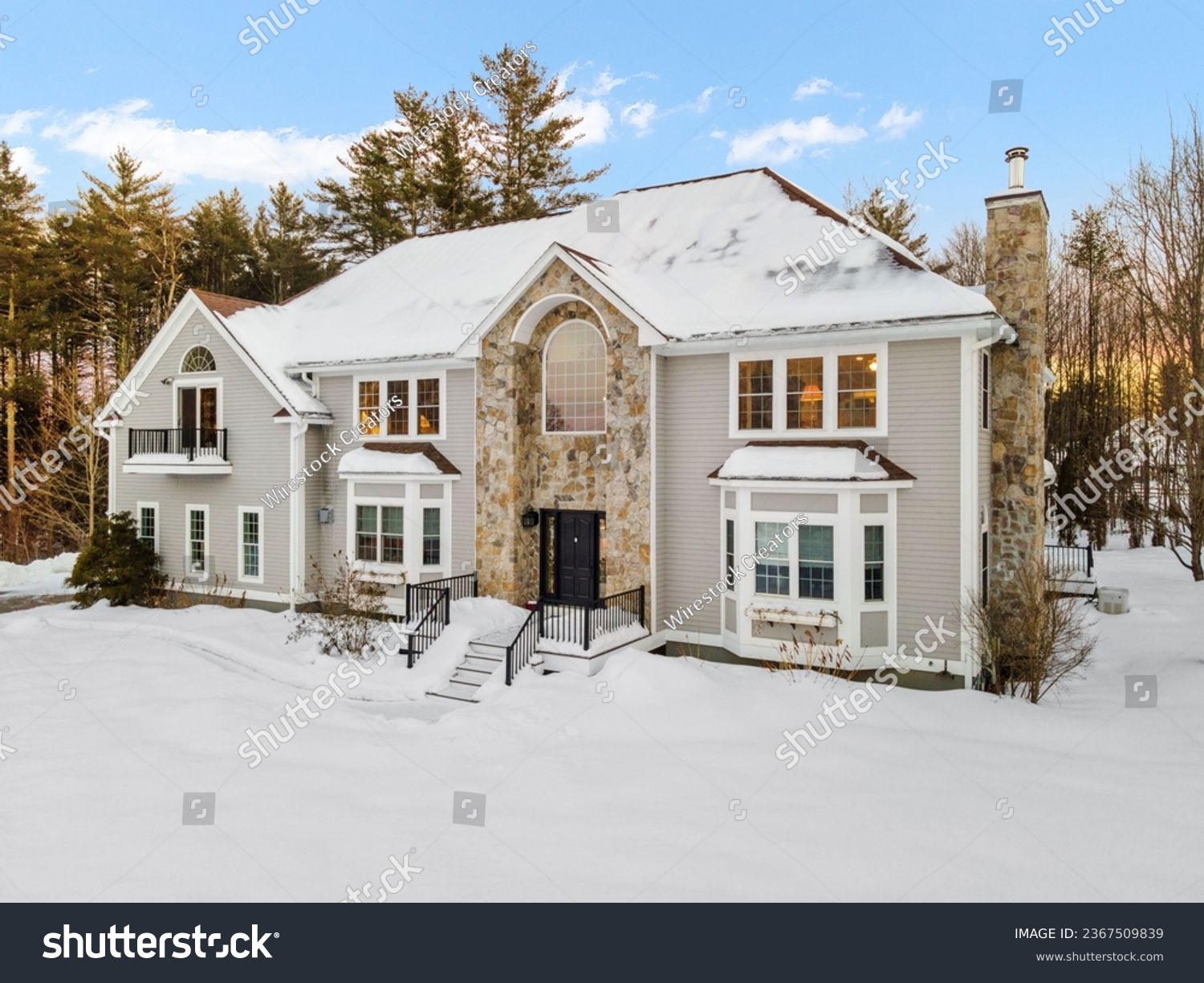 A modern two-story house on snowy winter landscapewith trees in New England #2367509839