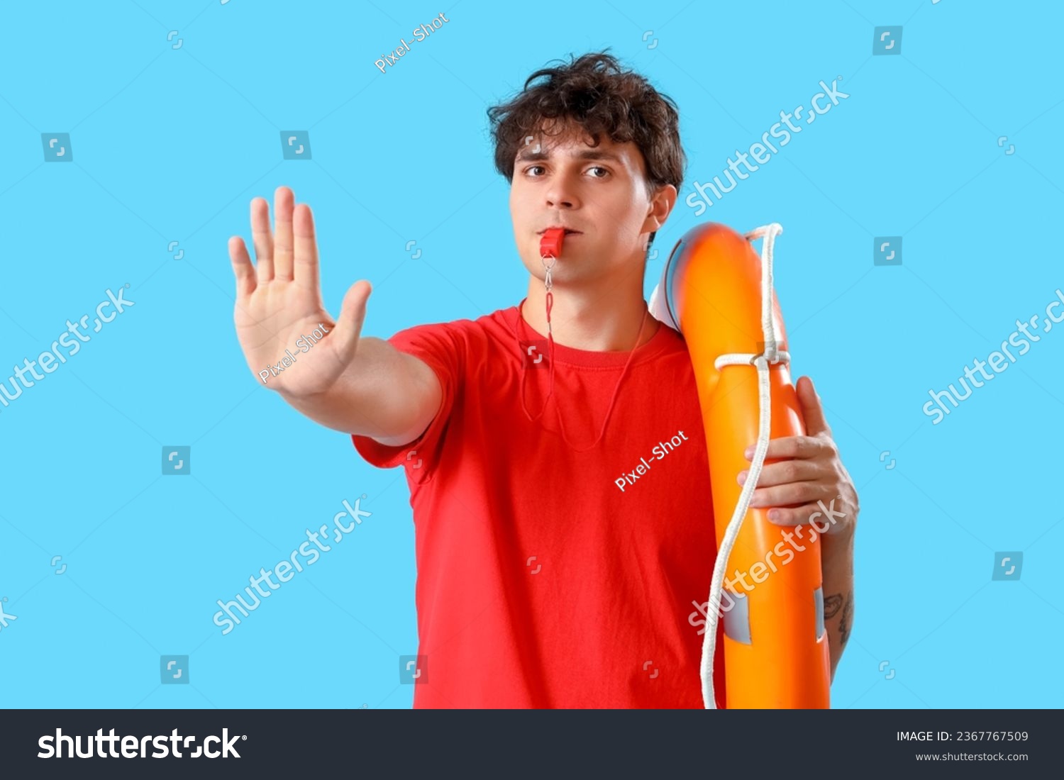 Male lifeguard with ring buoy and whistle showing stop gesture on blue background #2367767509