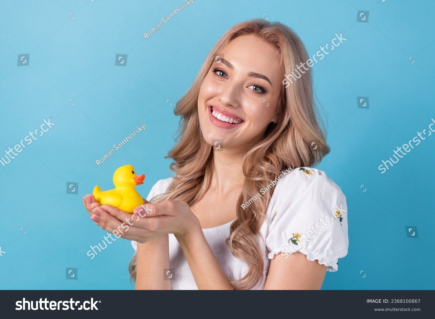 Photo of sweet shiny woman dressed white top smiling holding hands little yellow duck isolated blue color background #2368100867