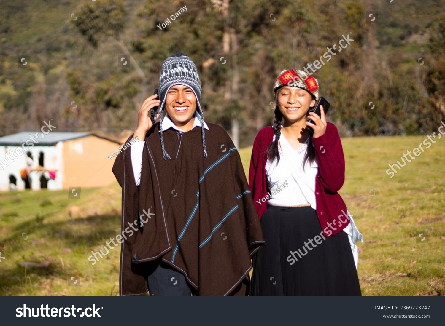 Quechua native man wearing a chullo, poncho and phone next to an attractive woman holding cell phone in her hand, outdoors, communication #2369773247