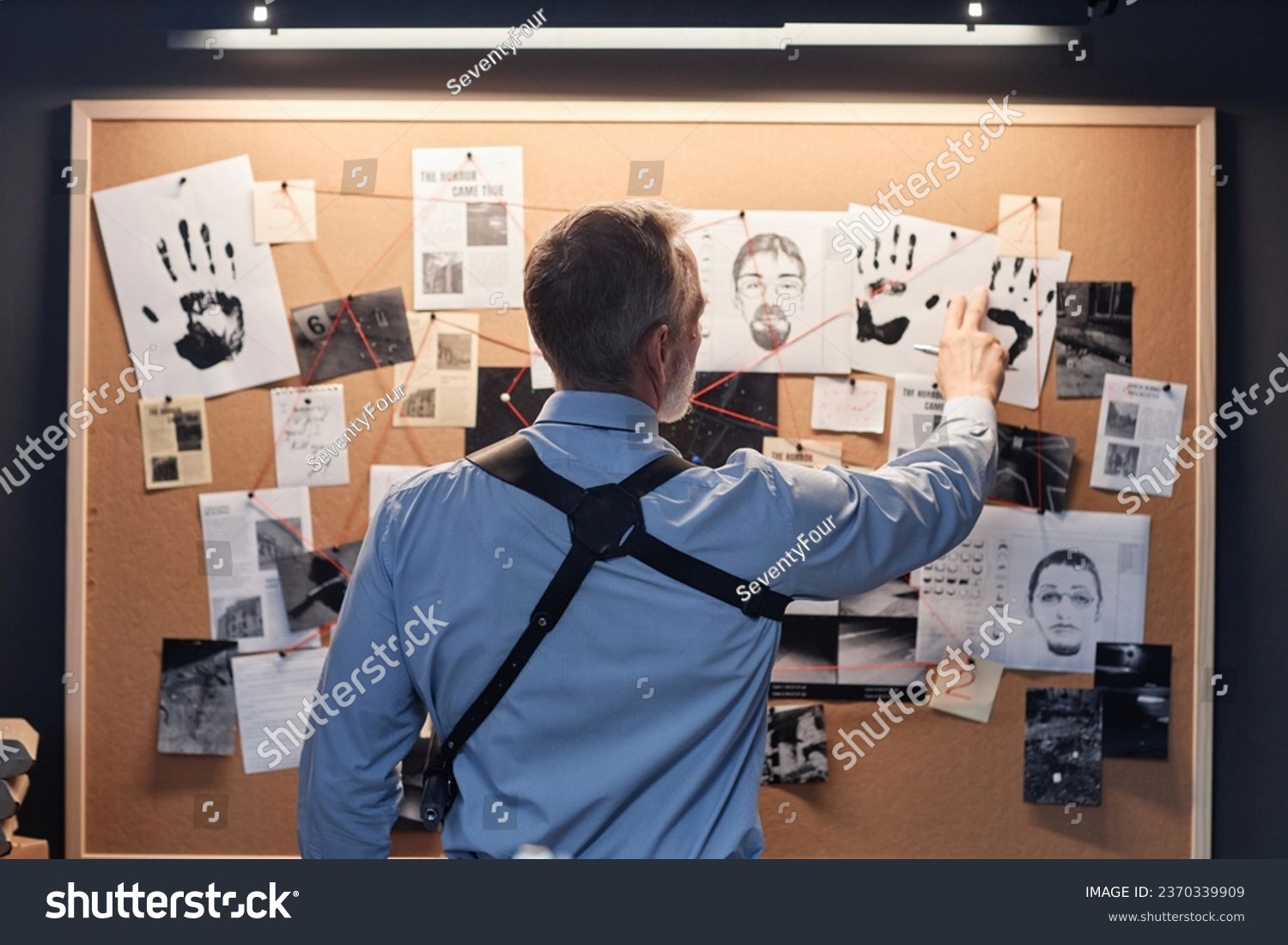 Back view of senior detective standing by evidence board and studying leads in investigation #2370339909