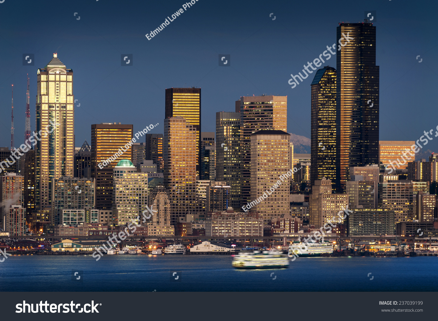 Seattle, Washington Skyline. Shot from West Seattle over Elliott Bay during a dramatic and lovely sunset. Ferryboats cross Elliott Bay heading to Bainbridge Island filled with commuters. #237039199