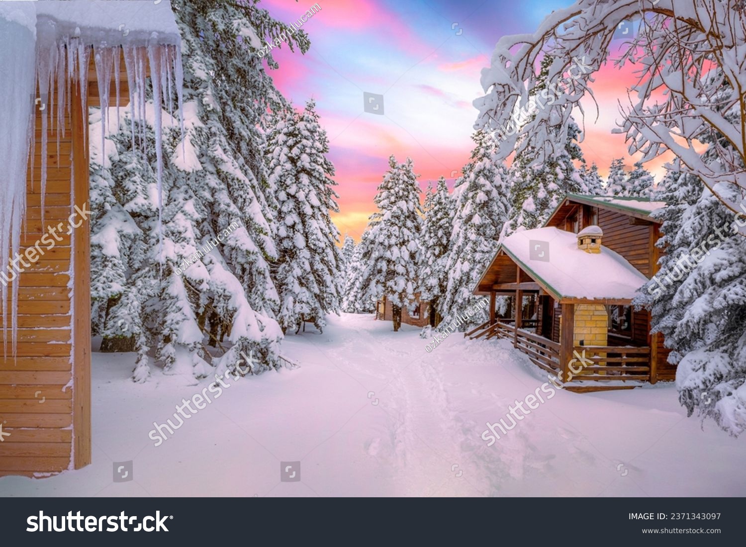 Snowy winter landscape in beautiful view of colorful sunset with wooden forest houses in cold snowy mountains at christmas time. Winter wonderland in snowy forest. Uludag mountain, Bursa city, Turkey. #2371343097