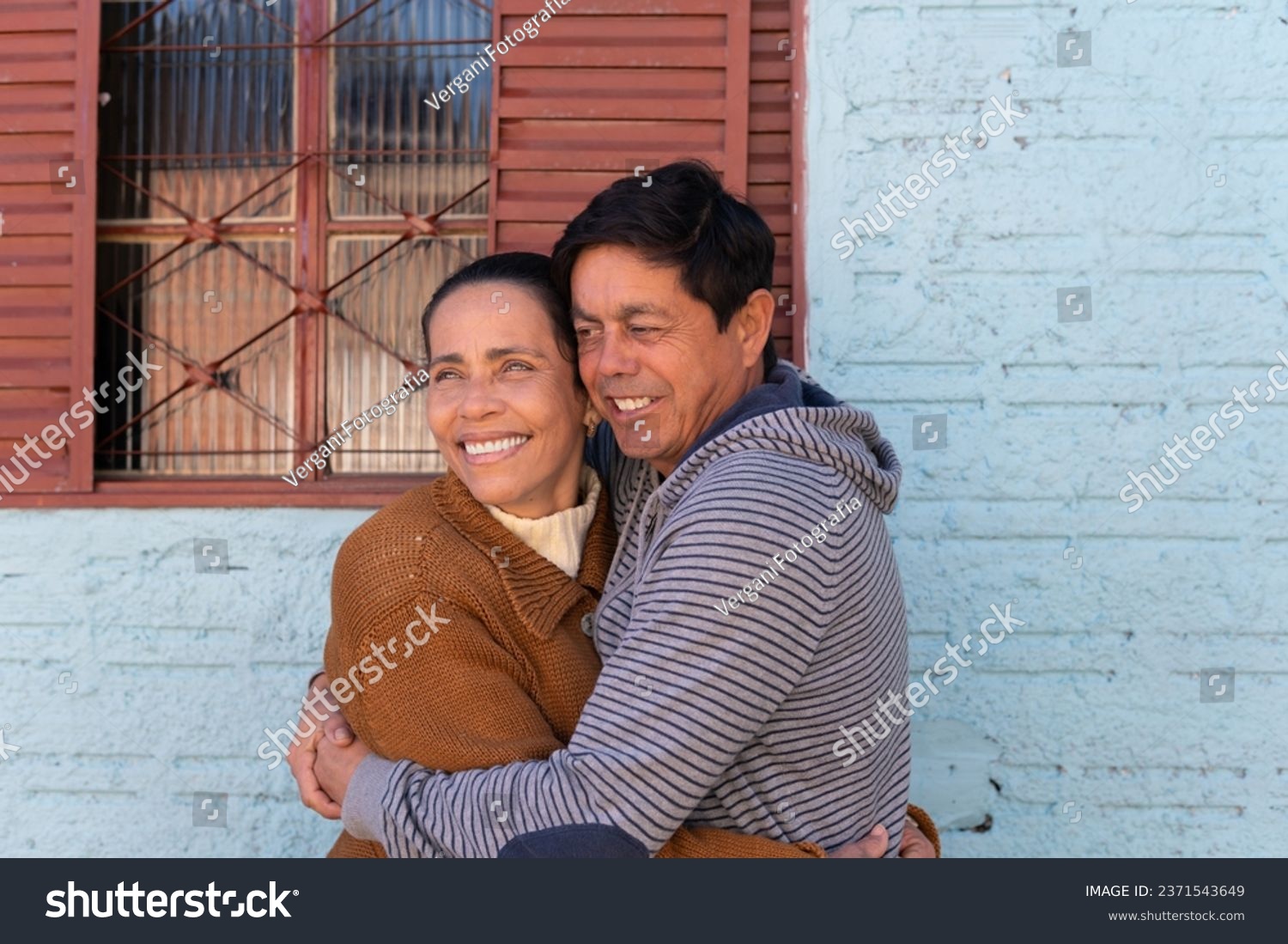 Cheerful Mature couplestanding and embracing each other outside the house. Togetherness, multi-generation family, support concept. #2371543649