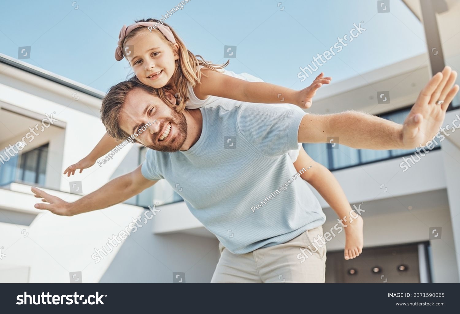 Portrait, girl and flying on back of her dad in a backyard of a home for real estate or property ownership. Love, children or family with a father and daughter in celebration of financial freedom #2371590065
