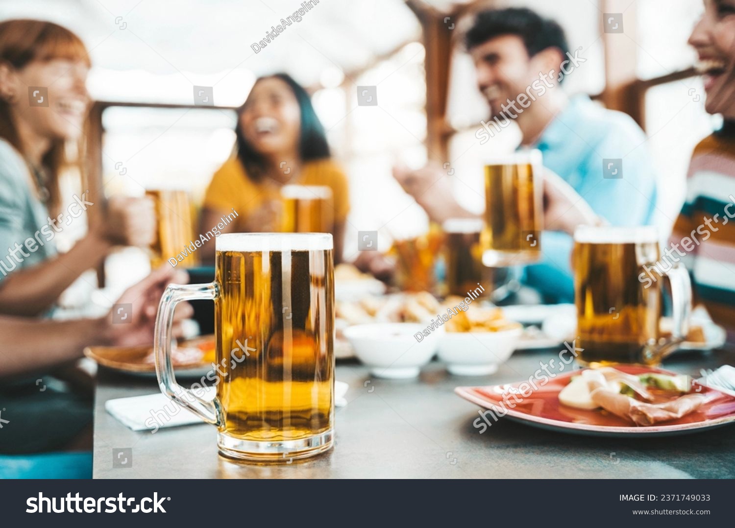 Happy people drinking beer at brewery pub restaurant - Group of friends enjoying happy hour sitting at bar table - Brewery life style concept with guys and girls dining together #2371749033