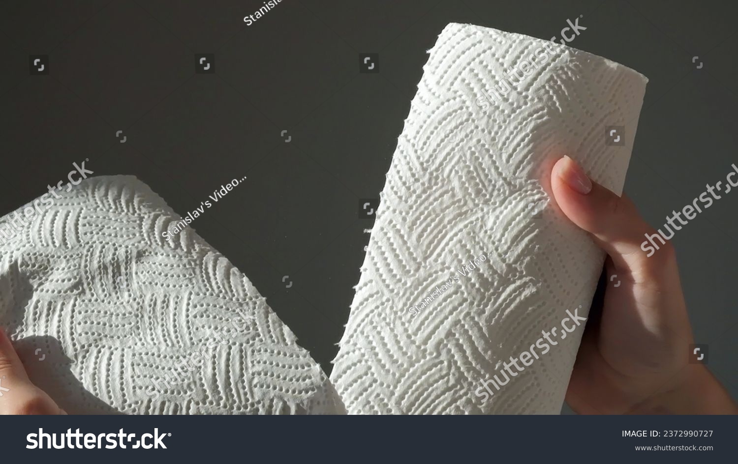 Female hands tear off piece of white paper towel from a roll. House cleaning concept. Close up, daylight. High quality photo #2372990727