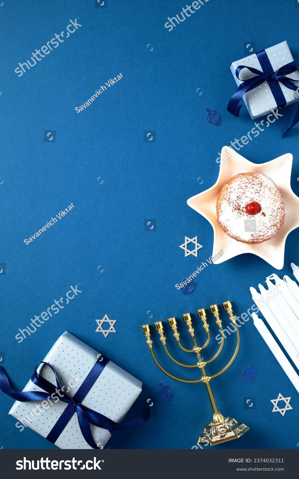 Hanukkah Jewish holiday vertical background with gold menorah, gift boxes, candles, traditional donut with jam on blue table. Flat lay, top view. #2374032311