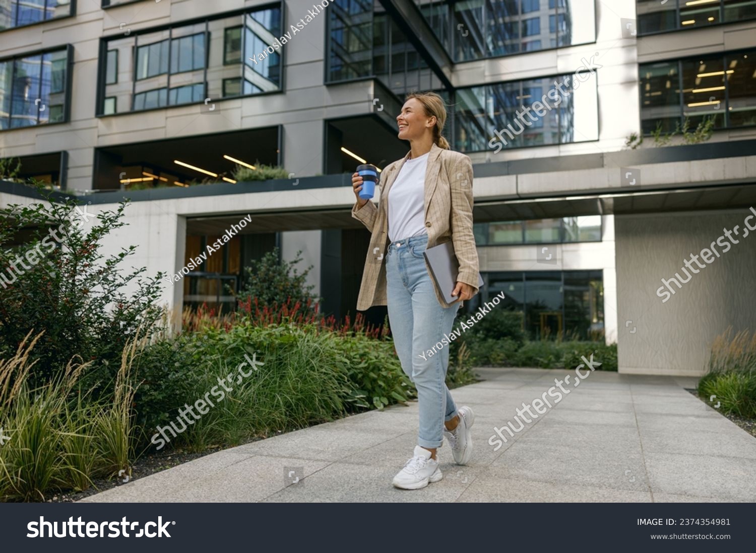 Stylish business woman drinking coffee during break time near office building and looks away #2374354981